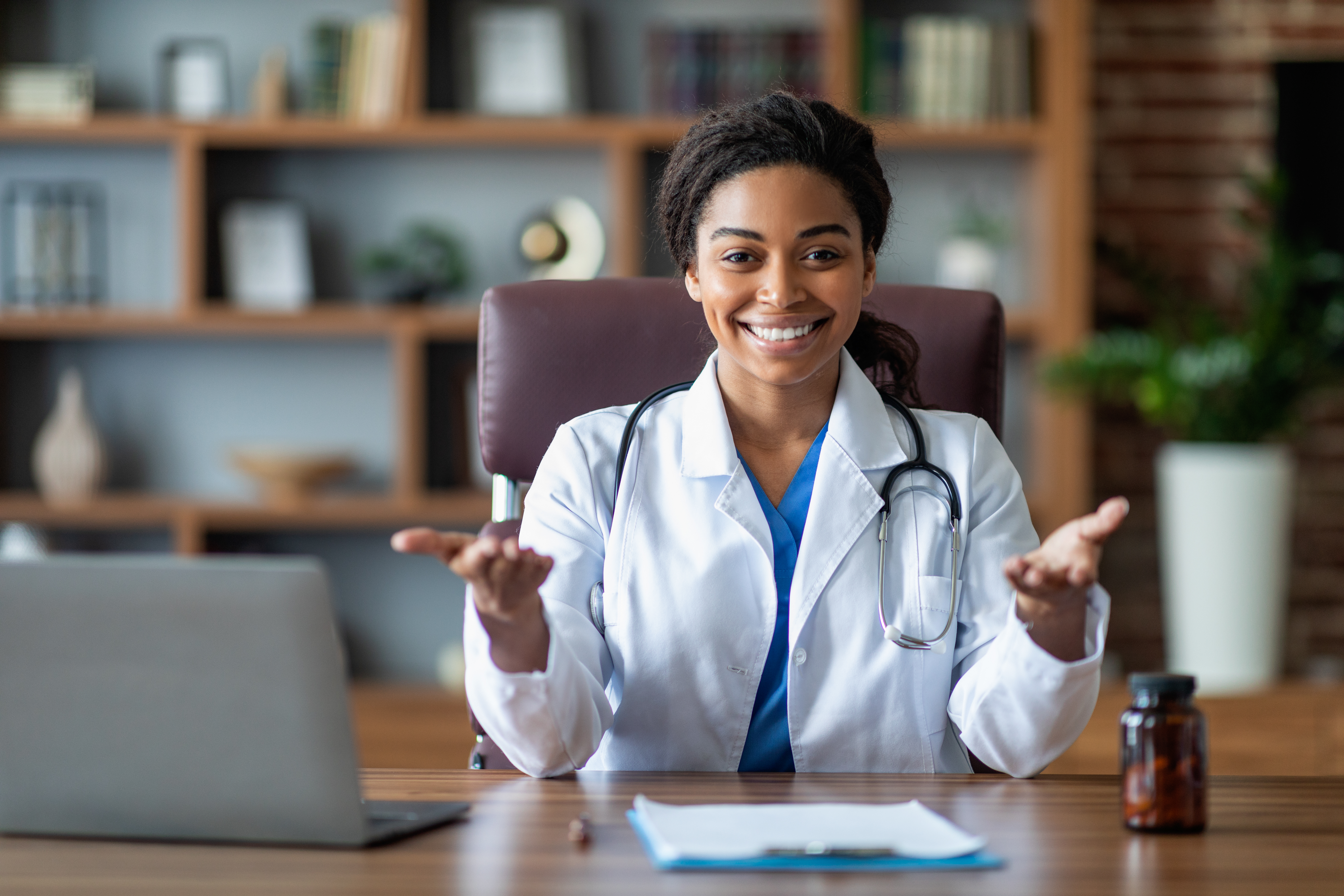 Doctor black woman in white robe with stethoscope at workplace